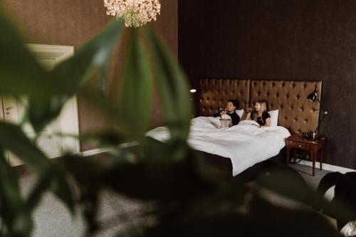 two people laying in bed in a hotel room at Châteauhotel De Havixhorst in Schiphorst