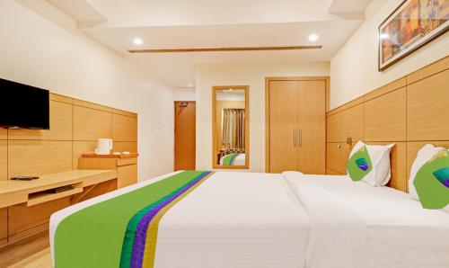 a bedroom with a large white bed and a desk at Treebo Galaxy Rooms in New Delhi