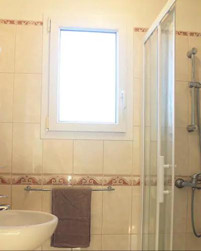 une salle de bain avec un lavabo et une douche avec une fenêtre dans l'établissement Maison calme et idéalement placée caen/st contest, à Cambes-en-Plaine