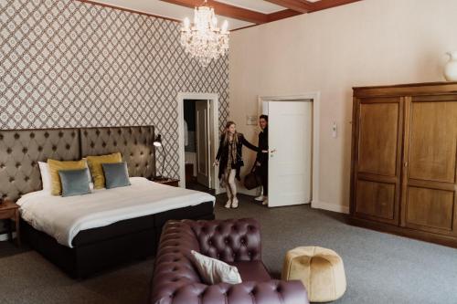 a woman walking into a hotel room with a bed at Châteauhotel De Havixhorst in Schiphorst