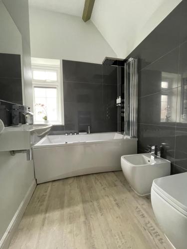 ein Badezimmer mit einer Badewanne, einem WC und einem Waschbecken in der Unterkunft Village Retreat & Hot Tub Nr Bicester Village in Bucknell