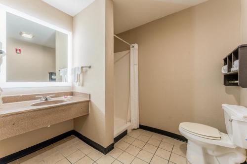 a bathroom with a toilet and a sink and a mirror at Super 8 by Wyndham Lake Charles Northeast in Lake Charles
