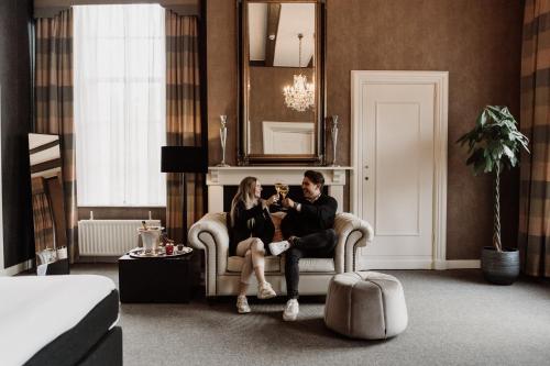 a man and woman sitting on a couch in a hotel room at Châteauhotel De Havixhorst in Schiphorst