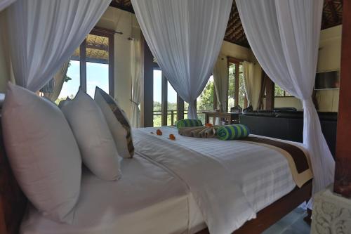 a bedroom with a white bed with white curtains at Bali Ubud Villa View in Ubud