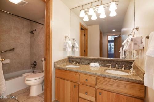 a bathroom with two sinks and a toilet and a mirror at Slopeside 2 Bedroom Gold-rated Residence At Golden Peak In Vail Village in Vail