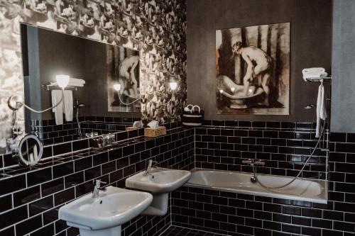 a bathroom with two sinks and a bath tub at Châteauhotel De Havixhorst in Schiphorst
