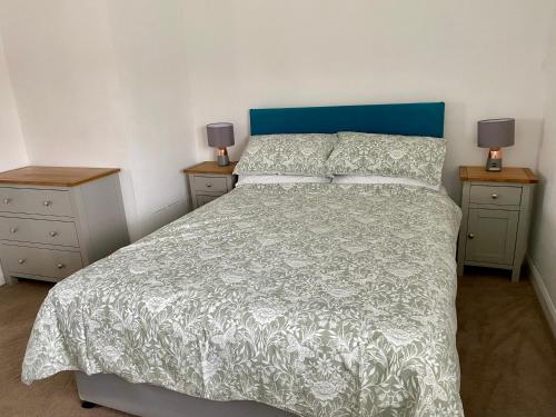a bedroom with a bed with a blue headboard and two night stands at Sunnyhill in Witley