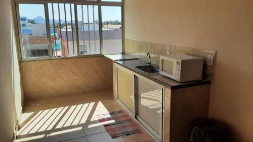 a kitchen with a microwave on a counter with a window at Pousada Campo Verde in Guarapari