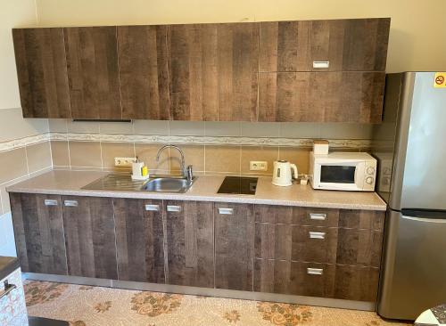 Una cocina con armarios de madera, fregadero y microondas. en Gaisma, en Ventspils