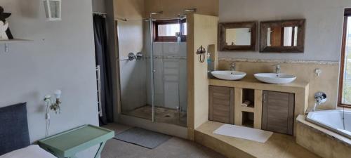 uma casa de banho com 2 lavatórios e uma cabina de duche em vidro. em Die Pastorie em Caledon