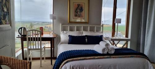 1 dormitorio con 1 cama con toallas y ventana en Die Pastorie, en Caledon