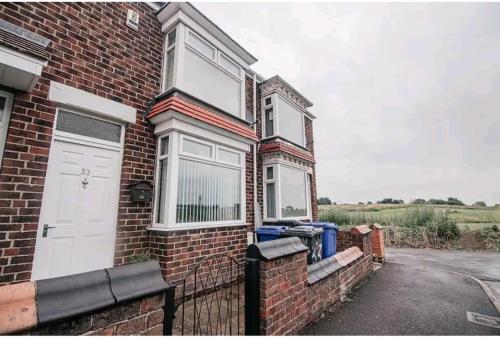 een stenen huis met een witte deur en een poort bij Fieldside View, Contractors and Families in Doncaster