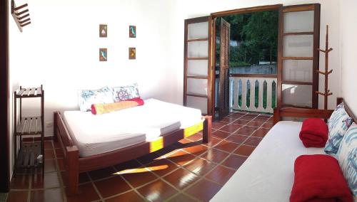 a room with two beds and a balcony at Casa Azul in Caraguatatuba