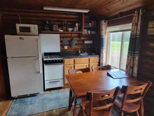 een keuken met een houten tafel en een witte koelkast bij Two Rivers Motel and Cabins 