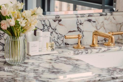 a bathroom counter with a vase of flowers and a sink at Hotel Barrière Fouquet's New York in New York