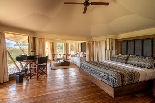 ein Schlafzimmer mit einem Bett und einem Schreibtisch in einem Zimmer in der Unterkunft Aurari Camp in Serengeti-Savanne