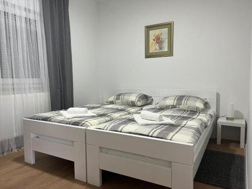 a white bed in a room with a white wall at Apartman F&F 2 in Otočac