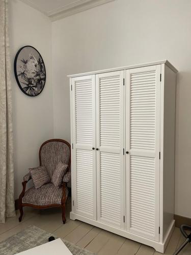 a white closet with a chair and a clock on a wall at Apartment- La Rochelle historic city centre in La Rochelle