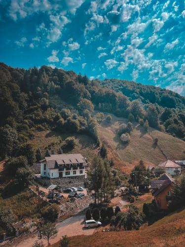 a house on a hill with cars parked in a parking lot at Valea lui Bogdan in Moieciu de Jos