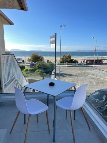 uma mesa e cadeiras numa varanda com vista para a praia em Hostal montevideo em Nigrán