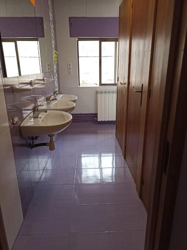Baño con 3 lavabos y una fila de espejos en Albergue de Siresa en Siresa