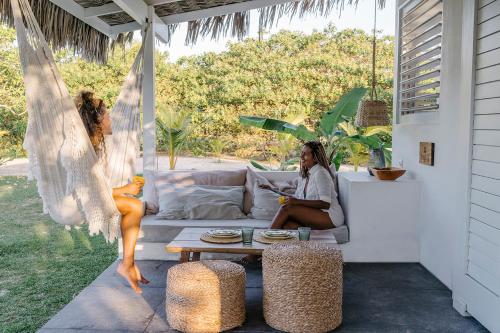 a woman sitting on a couch on a patio at Limbo Atins Chalets - Lençóis Maranhenses in Atins