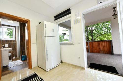 a kitchen with a white refrigerator and a bathroom at Lora in Rakovica