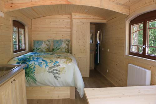 a bedroom in a log cabin with a bed at Les roulottes a Sandie in Thionville