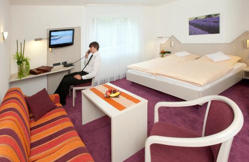 Hotel Malchen Garni في زيهايم يوغنهايم: رجل يجلس في مكتب في غرفة الفندق