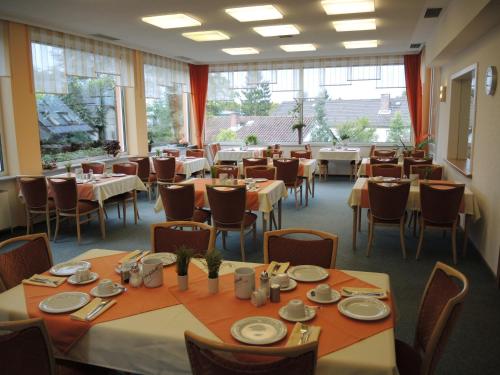 a dining room with tables and chairs and windows at Hotel Malchen Garni in Seeheim-Jugenheim