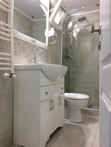 a white bathroom with a sink and a toilet at Solaria House in Constanţa