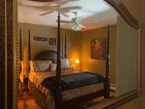 1 dormitorio con 1 cama con ventilador de techo y espejo en Toba's Bed & Breakfast, en East LaHave