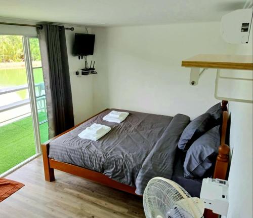 a bedroom with a bed with a fan and a window at บังกะโลบ้านสวนเอก Bungalow Baan Suan Aek in Ban Pang Chaphlung