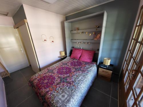 a small bedroom with a bed with pink pillows at Logement proche de Bordeaux, route des Châteaux in Ludon-Médoc