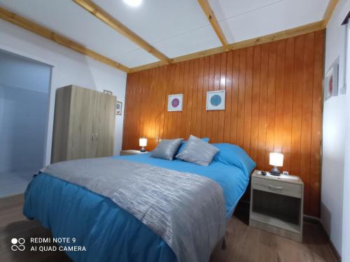 ein Schlafzimmer mit einem blauen Bett und einer Holzwand in der Unterkunft Loft Tongoy Peninsula sin estacionamiento in Coquimbo