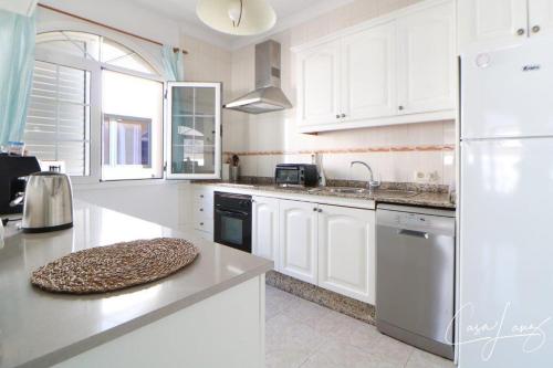 a kitchen with white cabinets and a white refrigerator at Cliff View Orzola in Orzola