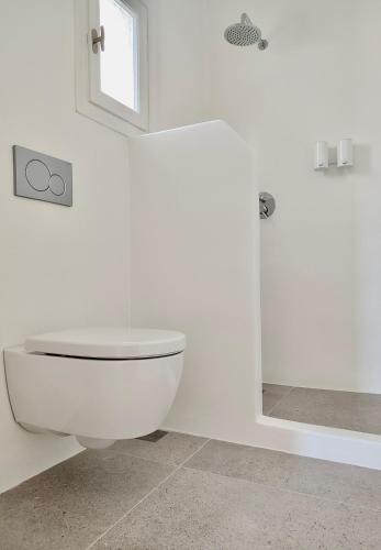 a white bathroom with a toilet and a shower at ARK Tinos in Agios Ioannis Tinos