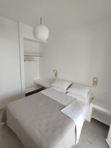 a white bedroom with a white bed and a desk at ARK Tinos in Agios Ioannis Tinos