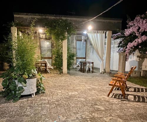 a patio at night with a table and benches at Masseria Montanari in Carpignano Salentino