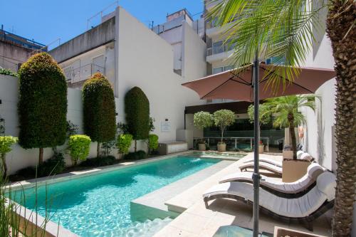 uma piscina com cadeiras e um guarda-sol ao lado de um edifício em Argenta Suites Belgrano em Buenos Aires