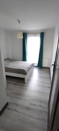 a bedroom with a bed and a window with green curtains at Biała Rzeka Rumia in Rumia