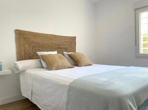 uma cama branca com lençóis brancos e almofadas em Precioso apartamento recién reformado em Cambrils