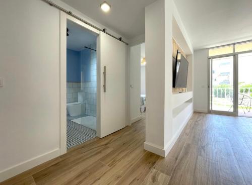 um corredor com paredes brancas e uma porta de vidro deslizante em Precioso apartamento recién reformado em Cambrils