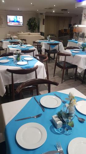 uma sala de jantar com mesas e cadeiras azuis e brancas em Garden Top Hotel em Joanesburgo
