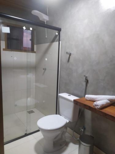 a bathroom with a toilet and a glass shower at Formosa Suites in Bonito