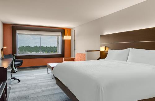 a hotel room with a bed and a desk and a window at Holiday Inn Express & Suites Sanford - Lake Mary by IHG in Sanford