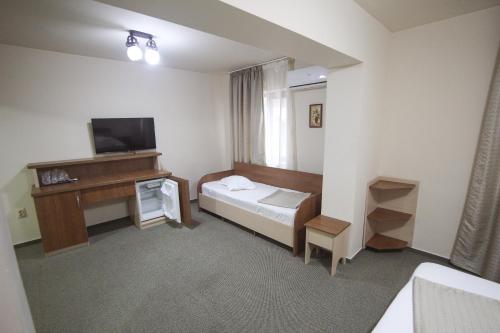 a room with a bed and a desk and a television at Teju Hotels in Slănic