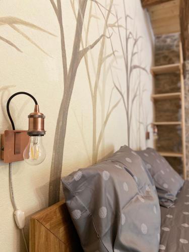 a lamp on a wall with a tree mural at La Fnera in Cavaliggi