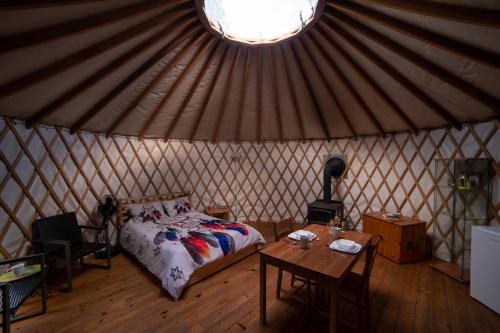 a room with a bed and a table in a yurt at La Lumineuse des yourtes du petit ruisseau in Mandeville