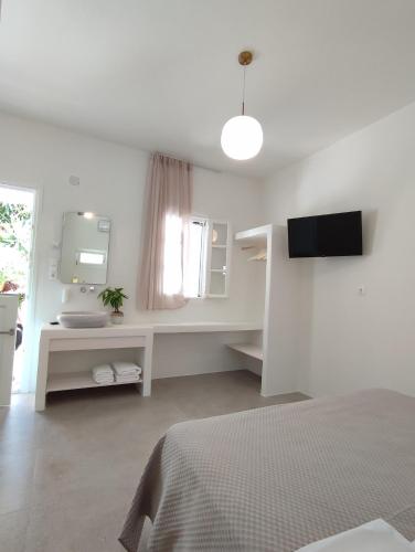 a white bedroom with a bed and a mirror at ARK Tinos in Agios Ioannis Tinos